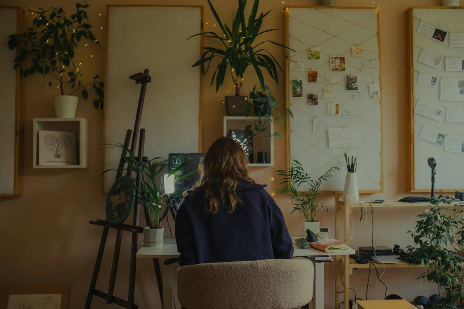 A plant-filled studio with a moodboard and warm light